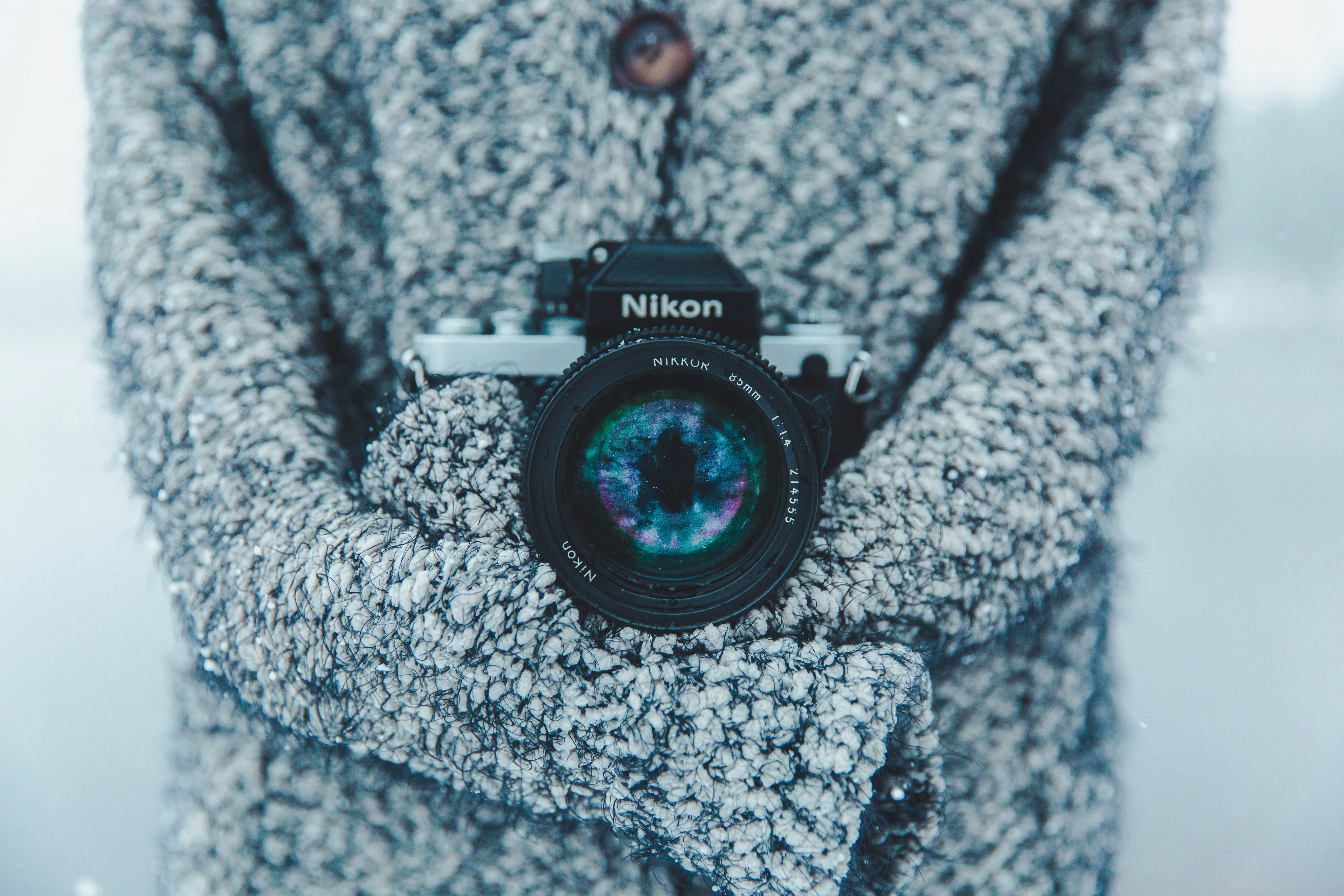person holding black and gray Nikon DSLR camera
